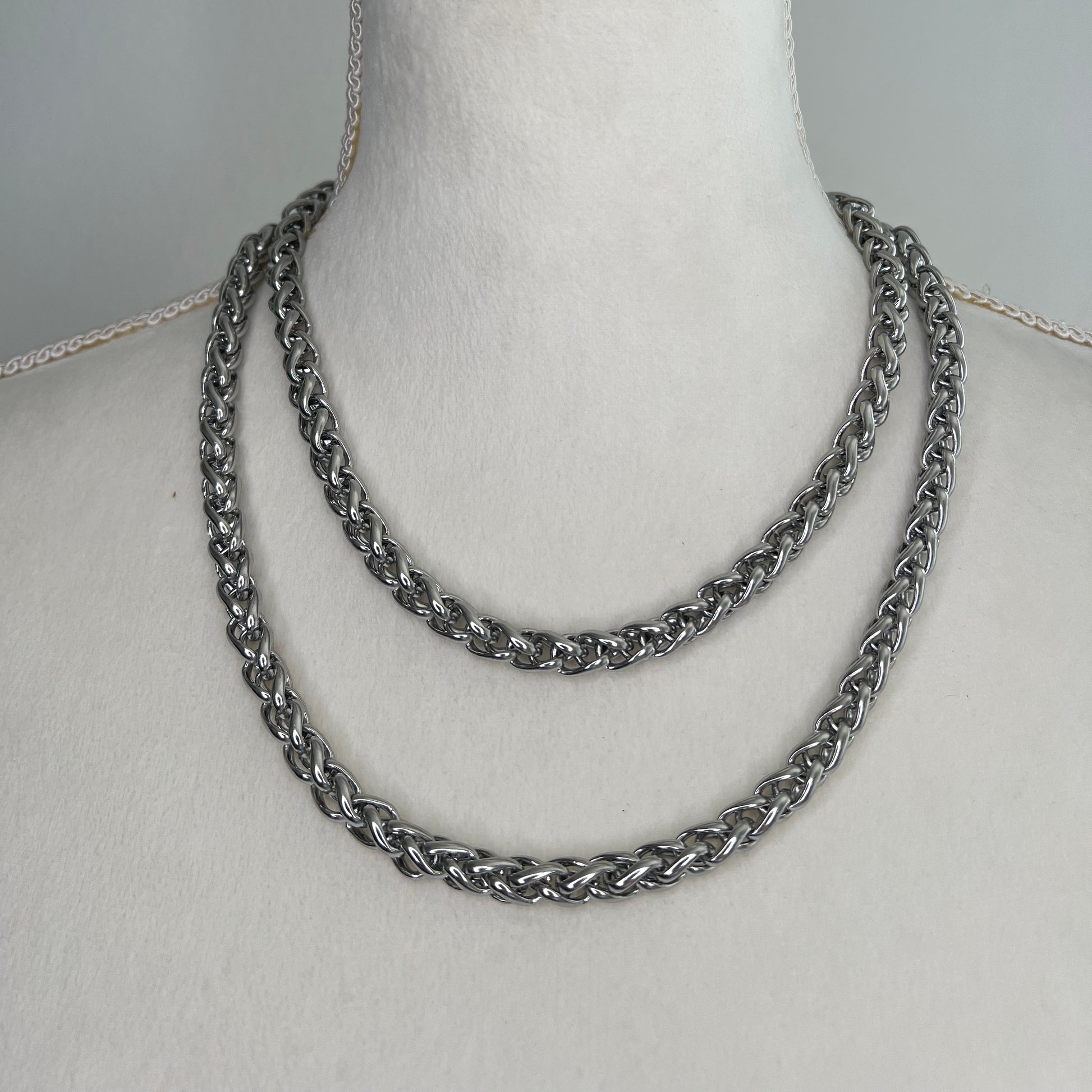 Silver chain necklace on a mannequin bust against a gray background