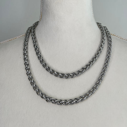 Silver chain necklace on a mannequin bust against a gray background