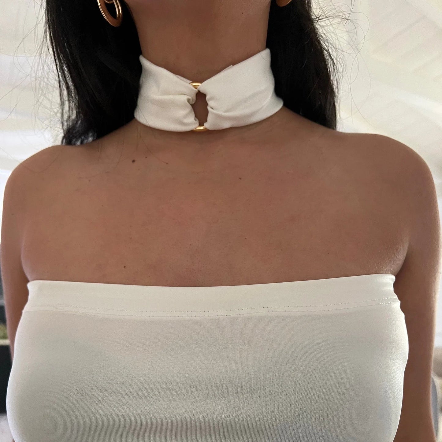 This image features an elegant white faux leather choker necklace, designed with a luxurious touch. The necklace is adorned with a central O-ring embellished with an 18K gold-plated stainless steel ring, adding a touch of sophistication and glamour.