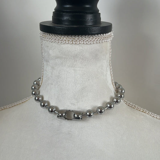 A silver-colored ball chain choker necklace displayed on a mannequin.